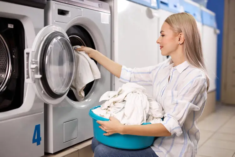 woman-placing-clothes-into-washer-in-laundromat.jpg