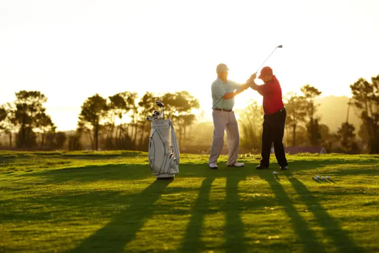 golf-instructor-helping-senior-player-sunset.jpg