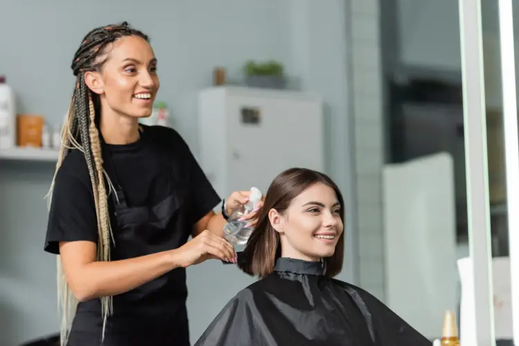 braided-hairdresser-spraying-hair-of-smiling-client.jpg