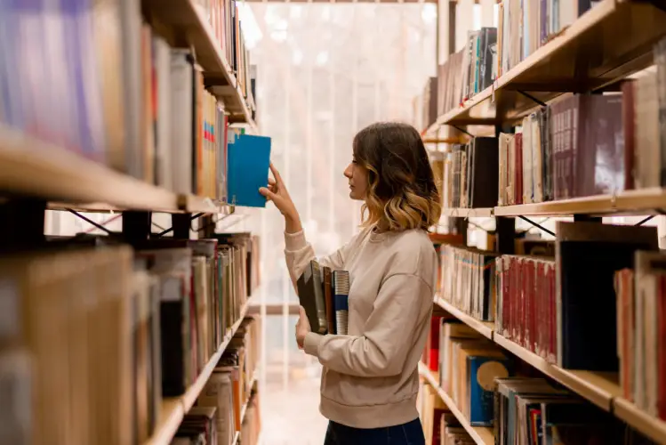 young-woman-picking-book-in-library-aisle.jpg