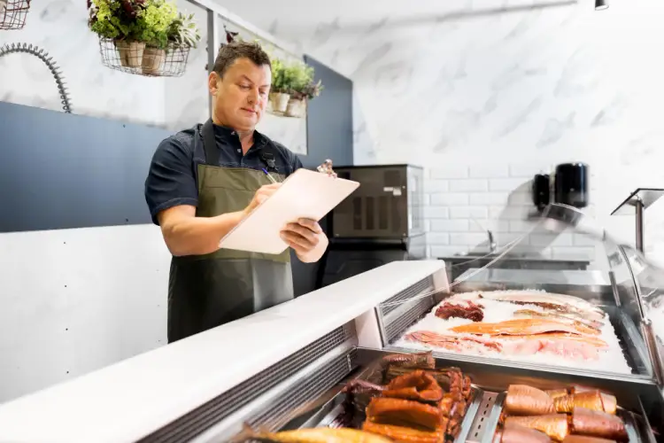 fishmonger-checking-inventory-at-seafood-counter.jpg