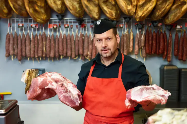 butcher-holding-fresh-cuts-in-cured-meats-shop.jpg
