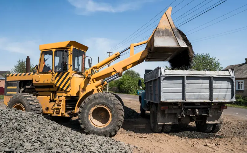 wheel-loader-dumping-rocks-into-dump-truck.jpg