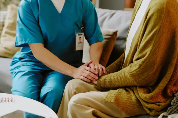 healthcare-worker-holding-hands-with-patient-on-couch.jpg