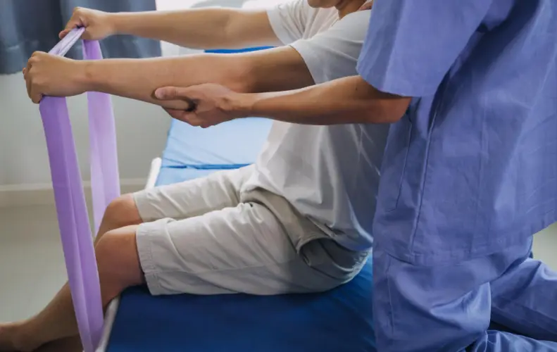 therapist-assisting-patient-resistance-band-rehab.jpg