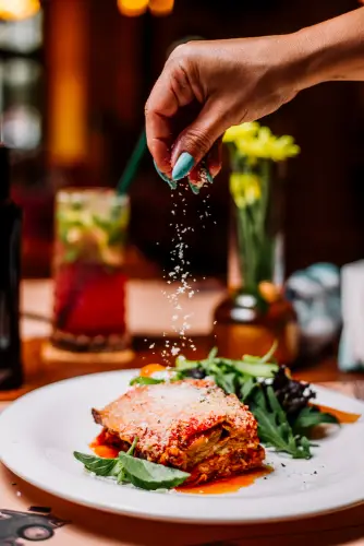 lasagna_plate_hand_sprinkling_parmesan.jpg